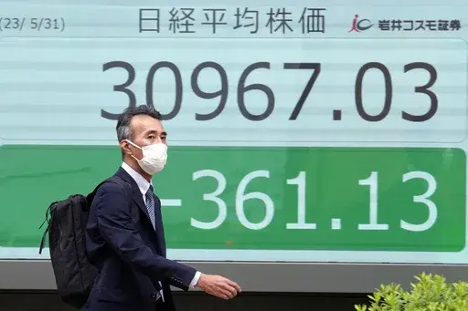 A person walks past an electronic stock board showing Japan's Nikkei 225 index at a securities firm Wednesday, May 31, 2023, in Tokyo. Asian stock markets sank Wednesday ahead of a vote by Congress on a deal to avert a government debt default, while a downturn in Chinese factory activity deepened, adding to signs global economic activity is weakening.(AP Photo/Eugene Hoshiko)