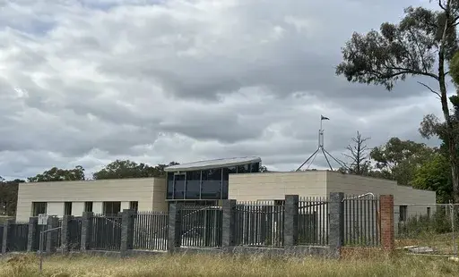 THIS CORRECTS THE PHOTOGRAPHER'S NAME TO MCGUIRK - The Australian flag flies on Parliament House, seen behind an unoccupied building on the grounds of a proposed new Russian embassy near the Australian Parliament in Canberra, Feb. 28, 2023. Australia's House of Representatives passed legislation Thursday, June 15, 2023, to prevent Russia from building a new embassy near Parliament House on security grounds. (AP Photo/Rod McGuirk)