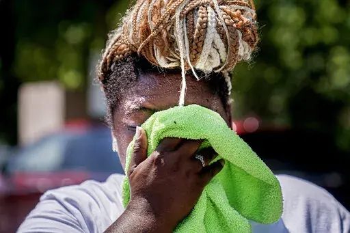 Nicole Brown wipes sweat from her face while setting up her beverage stand near the National Mall on July 22, 2022, in Washington. What's considered officially “dangerous heat” in coming decades will likely hit much of the world at least three times more often as climate change worsens, according to a new study. (AP Photo/Nathan Howard, File)