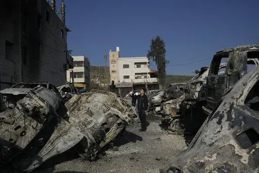 Palestinians take photos of burned cars in the town of Huwara, near the West Bank city of Nablus, Monday, Feb. 27, 2023. Scores of Israeli settlers went on a violent rampage in the northern West Bank, setting cars and homes on fire after two settlers were killed by a Palestinian gunman. Palestinian officials say one man was killed and four others were badly wounded. (AP Photo/Majdi Mohammed)