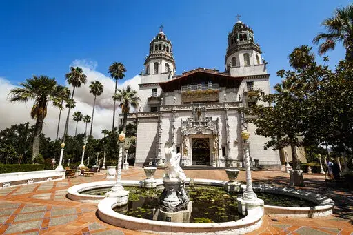 Smoke from a wildfire billows from a ridge line behind famed facade of Hearst Castle in San Simeon, Calif., on Aug. 20, 2016. California's famous Hearst Castle will reopen to the public in May, 2022, after a two-year closure due to the pandemic and severe rainstorm damage that prompted a $13.7 million renovation. (Joe Johnston/The Tribune of San Luis Obispo via AP, File)