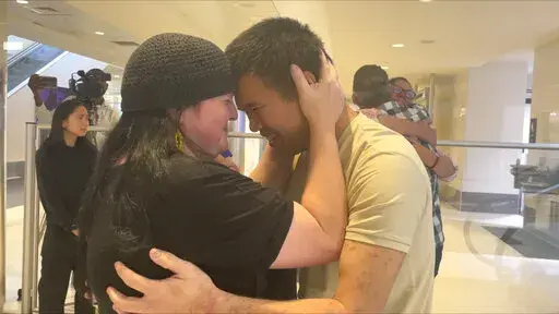 Andy Huynh, left, and Alex Drueke, far right, are seen hugging their loved ones after arriving at Birmingham-Shuttlesworth International Airport in Birmingham, Ala., Saturday, Sept. 24, 2022. The U.S. military veterans disappeared three months ago while fighting Russia with Ukrainian forces. They were released earlier this week by Russian-backed separatists as part of a prisoner exchange. (AP Photo/Kim Chandler)