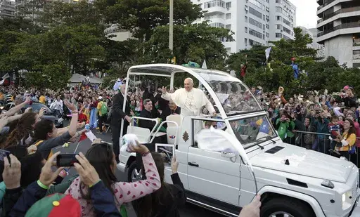 Pope Francis waves to people from his popemobile along the Copacabana beachfront as he arrives for the Stations of the Cross procession in Rio de Janeiro, Brazil, Friday, July 26, 2013. When Pope Francis made the first foreign trip of his papacy, to Rio de Janeiro for World Youth Day in 2013, he urged young people to make a "mess" in their local churches, to shake things up even if it ruffled the feathers of their bishops. (AP Photo/Andre Penner, File)