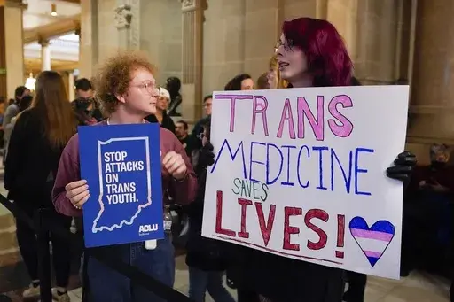 Protesters stand outside of the Senate chamber at the Indiana Statehouse on Feb. 22, 2023, in Indianapolis. Republican Governors in Indiana and Idaho have signed into law bills banning gender-affirming care for minors early April 2023, making those states the latest to prohibit transgender health care this year. (AP Photo/Darron Cummings, File)