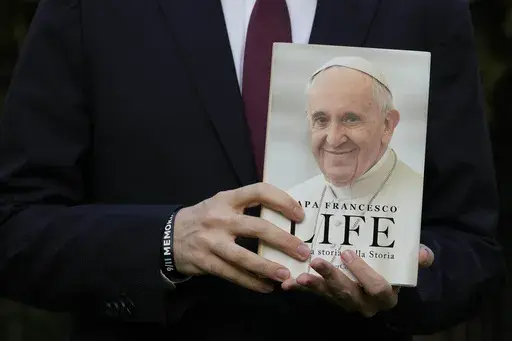 Italian journalist and writer Fabio Marchese Ragona holds a copy of "Life: My Story Through History" as he poses for a picture prior to the start of an interview with the Associated Press, in Rome, Thursday, March 13, 2024. Pope Francis says he has no plans to resign and isn't suffering from any health problems that would require doing so, in an autobiography, "Life: My Story Through History," which is being published Tuesday and written with Italian journalist Fabio Marchese Ragona. (AP Photo/G