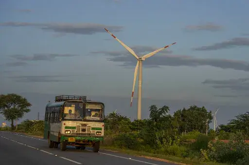 A bus drives past a windmill farm in Anantapur district, Andhra Pradesh, India, Sept 14, 2022. The key priority for India at the upcoming U.N. climate conference will be how to pay for the transition away from fossil fuels for energy and industries to meet temperature limit targets, according to a senior official who'll be part of the negotiations. (AP Photo/Rafiq Maqbool)