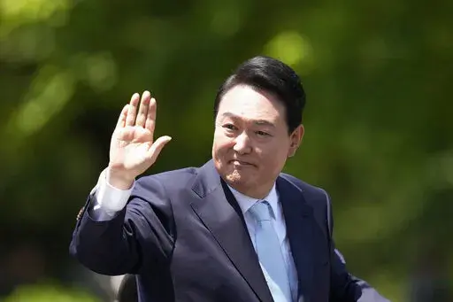 South Korea's new President Yoon Suk Yeol waves from a car after the Presidential Inauguration outside the National Assembly in Seoul, South Korea, Tuesday, May 10, 2022. (AP Photo/Lee Jin-man)