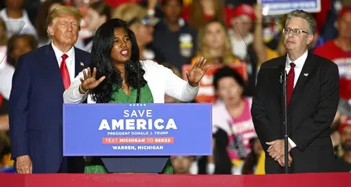 Former President Donald Trump, left, and Michigan Republican attorney general candidate Matt DePerno, right, listen as Michigan Republican secretary of state candidate Kristina Karamo addresses the crowd during a rally at the Macomb Community College Sports & Expo Center in Warren, Mich., Saturday, Oct. 1, 2022. With general election voting already underway in Michigan, Karamo stepped on stage as a warm-up act for Trump and hit hard on the main theme of her campaign -- repeating debunked asserti