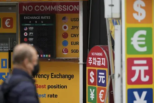 A man wearing a face mask walks past an electronic foreign currency exchange rates in downtown Seoul, South Korea, Wednesday, March 22, 2023. Asian shares advanced Wednesday after a Wall Street rally led by the banks most beaten down by the industry’s crisis.(AP Photo/Lee Jin-man)