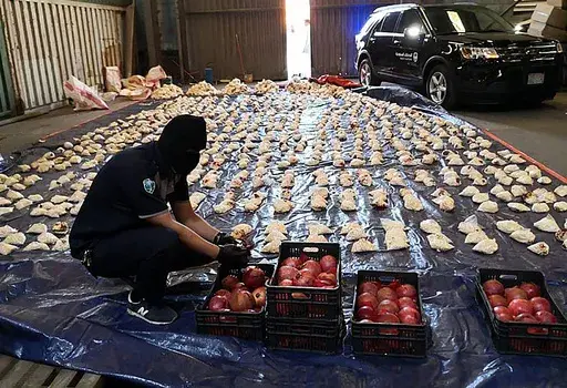 In this photo released by Saudi Press Agency, a Saudi custom officer opens imported pomegranates, as customs foiled an attempt to smuggle over 5 million pills of an amphetamine drug known as Captagon, which they said came from Lebanon, at Jiddah Islamic Port, Saudi Arabia, Friday, April 23, 2021. A little white pill has given Syrian President Bashar Assad powerful leverage with his Arab neighbors, who have been willing to bring him out of pariah status in hopes he will stop the flow of highly ad