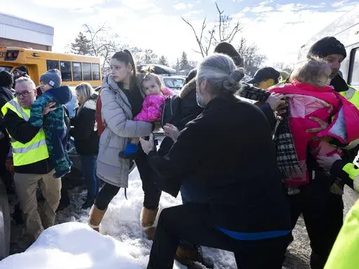 Parents and their children are loaded onto a warming bus as they wait for news after a bus crashed into a daycare centre in Laval, Quebec, on Wednesday, Feb. 8, 2023. (Ryan Remiorz/The Canadian Press via AP)