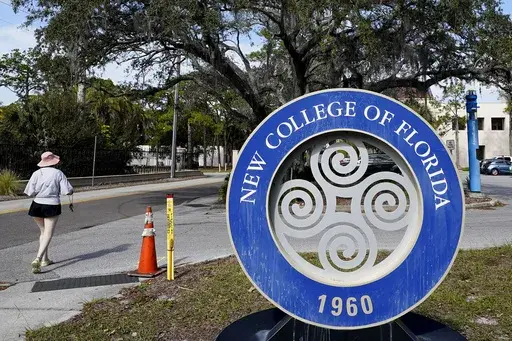 A student makes her way past the sign at New College of Florida, Jan. 20, 2023, in Sarasota, Fla. The New College of Florida trustees dominated by conservatives appointed by Gov. Ron DeSantis chose a new mascot on Thursday, June 1, 2023, for the Sarasota school: The Mighty Banyans. The tree mascot will replace one that has been in use since 1997, which is the mathematical formulation of the Null Set. (AP Photo/Chris O'Meara, File)