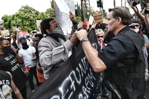 Los Angeles Captain Cory Palka, right reaches out and offers a handshake to a "Black Lives Matter" protester outside Los Angeles Mayor Garcetti's house in Los Angeles Tuesday, June 2, 2020. CBS and its former president, Leslie Moonves, will pay $30.5 million as part of an agreement with the New York attorney general's office, which says the network's executives conspired with a Los Angeles police captain later identified as Palka to conceal sexual assault allegations against Moonves. (AP Photo/R