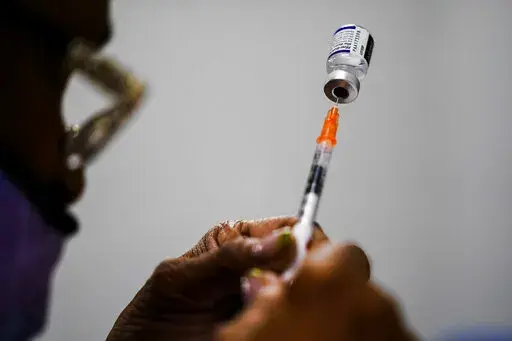 A syringe is prepared with the Pfizer COVID-19 vaccine at a vaccination clinic at the Keystone First Wellness Center in Chester, Pa., Dec. 15, 2021.  Pfizer says tweaking its COVID-19 vaccine to better target the omicron variant is safe and boosts protection. Saturday, June 25, 2022 announcement comes just days before regulators debate whether to offer Americans updated booster shots this fall. (AP Photo/Matt Rourke, File)