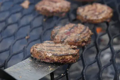 Hamburgers appear on a grill in Washington on Aug. 4, 2011. Most grillers recommend a mixture of 80% beef to 20% fat, but Craig “Meathead” Goldwyn, author of “Meathead, The Science of Great Barbecue and Grilling,” prefers even more fat, up to a 70:30 ratio. (AP Photo/Carolyn Kaster, File)