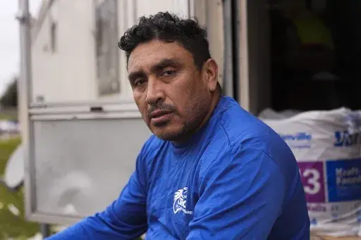 Mario Mendoza poses for a portrait as he takes a break while working on repairing a mobile home in Belle Chasse, La., Wednesday, Jan. 15, 2025, that was damaged from Hurricane Ida in 2021. (AP Photo/Gerald Herbert)