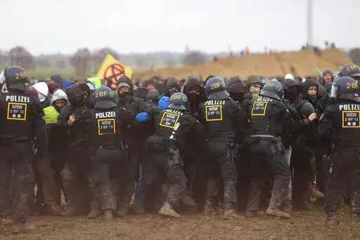 Police officers push back demonstrators on the edge of the opencast lignite mine Garzweiler at the village Luetzerath near Erkelenz, Germany, Saturday, Jan. 14, 2023. ( Oliver Berg/dpa via AP)
