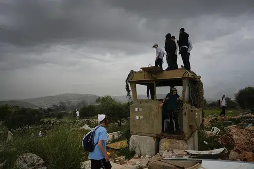 Israeli settlers stand in the outpost of Eviatar in the West Bank, Monday, April 10, 2023. Thousands led by hardline ultranationalist Jewish settlers marched to the unauthorized settlement outpost Eviatar in the northern West Bank that was cleared by the Israeli government in 2021, protected by a large contingent of Israeli soldiers and police. (AP Photo/Ariel Schalit)