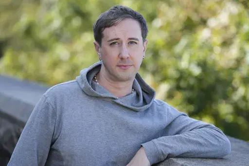 Samuel Schultz poses for a picture near his his home, Monday, Oct. 9, 2023 in New York. It took eight years and the burgeoning #MeToo movement to spur them to go public and make a police report, and an additional five years for their attackers to plead guilty. Now, as much as Schultz hopes there’s a reckoning coming in gay and queer communities, too, it feels like they are the one shouldering the blame, not the attackers: for coming forward, for harming the men’s reputations. (AP Photo/Seth 