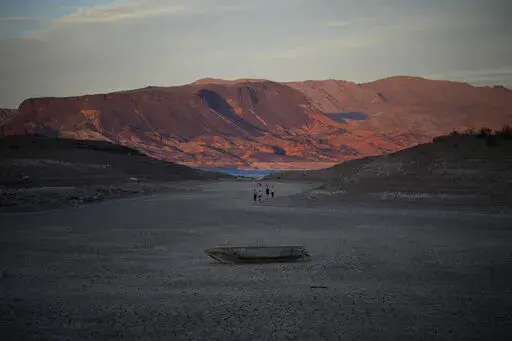 A formerly sunken boat sits on cracked earth hundreds of feet from what is now the shoreline on Lake Mead at the Lake Mead National Recreation Area, Monday, May 9, 2022, near Boulder City, Nev. Lake Mead is receding and Sin City is awash with mob lore after a second set of human remains emerged within a week from the depths of the drought-stricken Colorado River reservoir just a short drive from the Las Vegas Strip.  (AP Photo/John Locher)