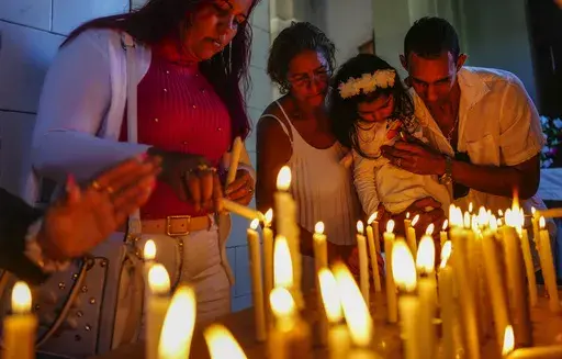 People light candles in honor of Cuba's patron saint, the Virgin of Charity of Cobre, at her shrine in El Cobre, Cuba, Feb. 11, 2024. The Vatican-recognized Virgin, venerated by Catholics and followers of Afro-Cuban Santeria traditions, is at the heart of Cuban identity. (AP Photo/Ramon Espinosa, File)