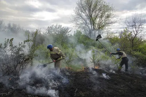 Rescue servicemen extinguish a bush fire after shelling in Mykolaivka, Donetsk region, eastern Ukraine, Friday, April 29, 2022. (AP Photo/Evgeniy Maloletka)