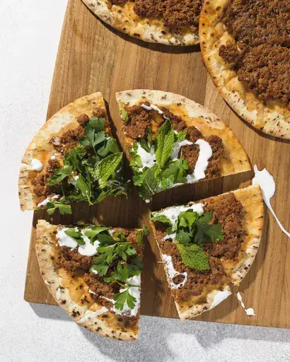 This image released by Milk Street shows a recipe for lahmajoun, a flatbread topped with spiced ground lamb, tomatoes and bell pepper. (Milk Street via AP)
