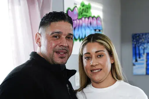 Eladio and Melissa Guzman pose for photographs, Monday, April 4, 2022, in Hicksville, N.Y. The couple, who endured the war on drugs, including jail time, are now eager to open a recreational marijuana dispensary in New York. (AP Photo/Frank Franklin II)