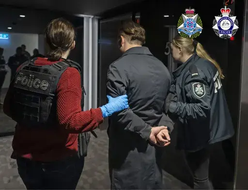 In this photo provided by the Australian Federal Police a man is taken into custody in Melbourne, Wednesday, June 14, 2023. A drug syndicate that tried to smuggle tons of methamphetamine from Canada to Australia and New Zealand by hiding it in shipments of maple syrup and canola oil has been busted, authorities said Thursday, June 15. (Australian Federal Police via AP)