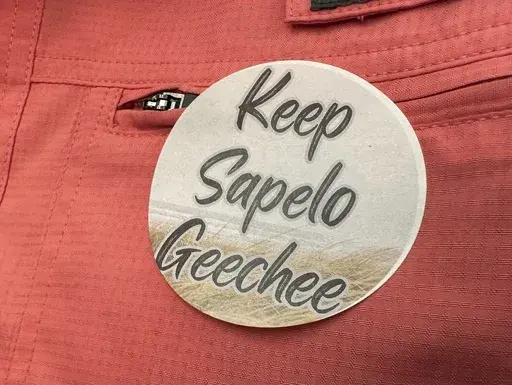 A sticker saying "Keep Sapelo Geechee" is worn on the shirt of George Grovner, a resident of the Hogg Hummock community on Sapelo Island, during a meeting of McIntosh County commissioners, Sept. 12, 2023, in Darien, Ga. A lawsuit by Black descendants of slaves that challenges zoning changes affecting their island homes is before a Georgia judge, who must decide whether to allow lawyers to amend the civil complaint to avoid having it dismissed. (AP Photo/Ross Bynum, File)