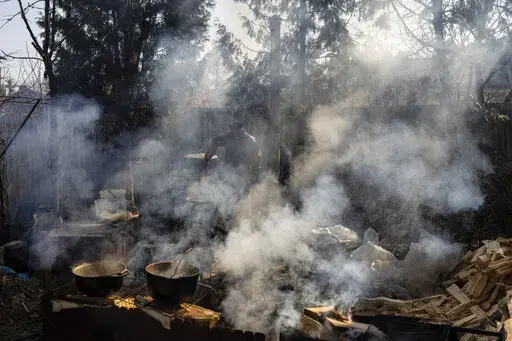 Volunteers cook in the courtyard of a theatre in the city of Drohobych, western Ukraine, Monday, March 21, 2022. The theatre has become a meeting point, where artists, including those displaced from other parts of Ukraine, have turned their talents to making food for soldiers and others as part of a massive volunteer war effort across the country. (AP Photo/Bernat Armangue)