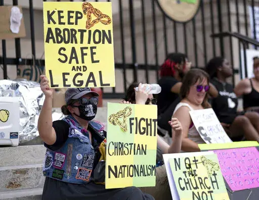 A small group, including Stephanie Batchelor, left, sits on the steps of the Georgia state Capitol protesting the overturning of Roe v. Wade on June 26, 2022. The Georgia Supreme Court on Wednesday, Nov. 23, reinstated the state’s ban on abortions after roughly six weeks of pregnancy. (AP Photo/Ben Gray, File)