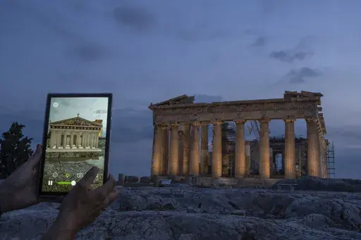 A man holds up a tablet showing a digitally overlayed virtual reconstruction of the ancient Parthenon temple, at the Acropolis Hill in Athens, Greece on Tuesday, June 13, 2023. Greece has become a late but enthusiastic convert to new technology as a way of displaying its famous archaeological monuments and deepening visitors' knowledge of ancient history. The latest virtual tour on offer is provided by a mobile app that uses Augmented Reality to produce digital overlays that show visitors at the