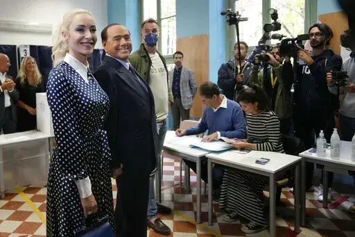  Silvio Berlusconi, leader of center-right, populist Forza Italia is flanked by his partner Marta Fascina, after casting his ballot at a polling station in Milan, Italy, Sunday, Sept. 25, 2022, in Milan, Italy.  Just in time to celebrate his 86th birthday, Italy’s former premier Silvio Berlusconi is making his return to Italy's parliament, winning a seat in the Senate nearly a decade after being banned from public office over a tax fraud conviction. (AP Photo/Antonio Calanni, File)