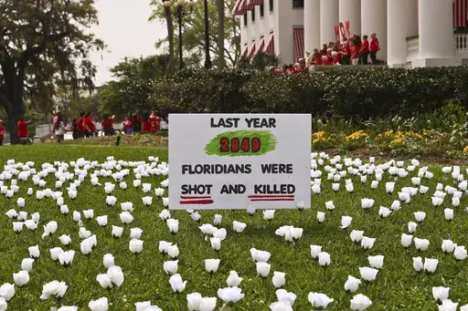 A sign and about 2,849 white silk roses, planted by South Florida members of Moms Demand Action to symbolize Floridians shot and killed last year, in front of the Old Capitol, March 9, 2023 at the Capitol in Tallahassee, Fla. (AP Photo/Phil Sears, file)