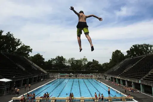 A boy jumps into the water at the Olympic open air public pool in Berlin, Germany, May 21, 2014. Women in Berlin will soon be allowed to go topless at the city's public pools, the Berlin state government said Thursday. The new bathing rules to allow both men and women to go swimming without covering their upper bodies came in reaction to a woman's complaint alleging discrimination because she was not allowed to swim topless in a swimming pool in Berlin, like men. (AP Photo/Markus Schreiber, File