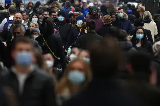 Shoppers walk down Oxford Street, Europe's busiest shopping street, in London, Dec. 23, 2021. The British government confirmed Saturday Feb. 19, 2022, that people with the coronavirus will not be legally required to self-isolate starting next week, as part of a plan for “living with COVID” that is also likely to see testing for the virus scaled back. (AP Photo/Frank Augstein, File)
