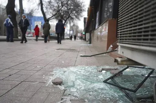 People walk past a shop with windows broken during clashes in Almaty, Kazakhstan, Monday, Jan. 10, 2022. Kazakhstan's health ministry says over 150 people have been killed in protests that have rocked the country over the past week. President Kassym-Jomart Tokayev's office said Sunday that order has stabilized in the country and that authorities have regained control of administrative buildings that were occupied by protesters, some of which were set on fire. (Vladimir Tretyakov/NUR.KZ via AP)