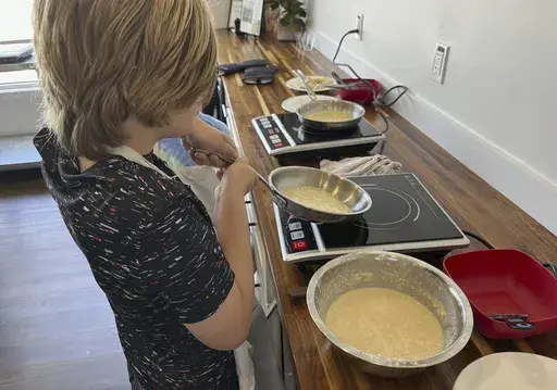This image shows a child making crepes at Third Space Kitchen, a facility offering kids cooking classes in Goton, Mass., on July 16, 2024. (Third Space Kitchen via AP)