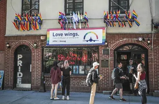 In this Monday, June 3, 2019, file photo, Pride flags and colors display on the Stonewall Inn bar, marking the site of 1969 riots that followed a police raid of the bar's gay patrons, in New York. A visitor center dedicated to telling the story of LGBTQ rights movement will open next door to the Stonewall Inn. Organizers say the groundbreaking for the Stonewall National Monument Visitor Center in New York City's Greenwich Village neighborhood will take place Friday, June 24, 2022. (AP Photo/Bebe