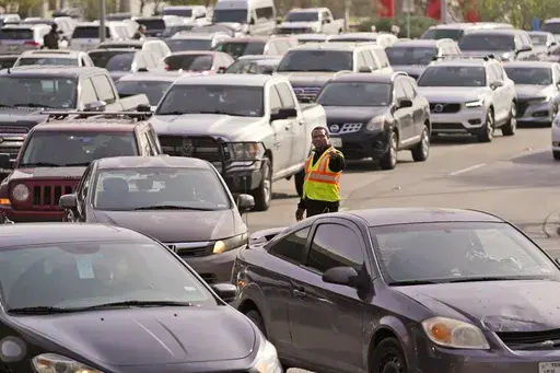 An officer directs traffic at Love Field Airport in Dallas, Wednesday, Dec. 21, 2022. The rate of people working from home dropped from 17.9% in 2021 to 15.2% in 2022, according to new survey data released Thursday, Sept. 14, 2023, by the U.S. Census Bureau on life in America, covering commuting times internet access, family life, income, education levels, disabilities, military service and employment. (AP Photo/LM Otero, File)