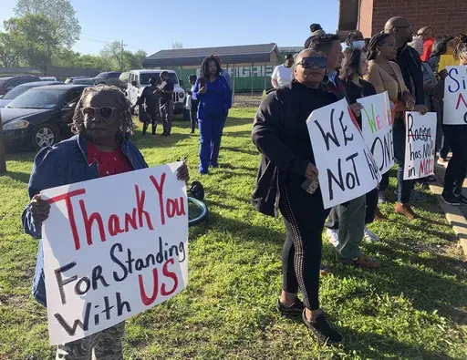 Glenda Austin of Idabel, Okla., holds a sign with other protesters, Monday, April 17, 2023, outside the McCurtain County Commissioners meeting room in Idabel, Okla. A number of McCurtain County residents were outraged by comments made by local officials on a recording and are asking for the resignation of the sheriff, two county commissioners and others. (Lori Dunn/The Texarkana Gazette via AP)