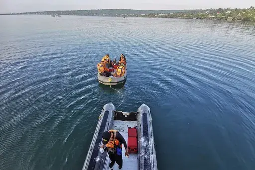 In this photo provided by the National Search and Rescue Agency (BASARNAS), rescuers on a rubber boat search for survivors after an overloaded ferry sank off Sulawesi Island, Indonesia, Monday, July 24, 2023. (BASARNAS via AP)