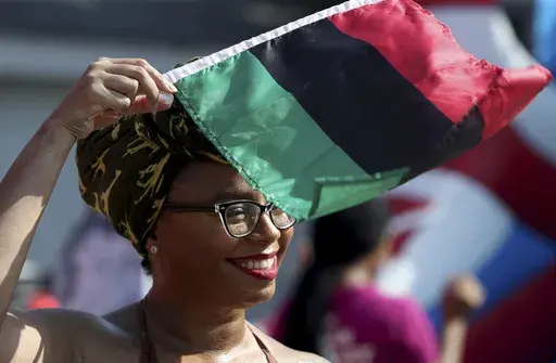 Crystal Baziel holds the Pan-African flag Monday, June 19, 2023, during Reedy Chapel A.M.E Church's annual Juneteenth Family Fun Day, in Galveston, Texas. Many Americans are celebrating Juneteenth, marking the day in 1865 when the last enslaved people in the U.S. learned they were free. For generations, Black Americans have recognized the end of one of history’s darkest chapters with joy, in the form of parades, street festivals, musical performances or cookouts. (Jennifer Reynolds/The Galvest