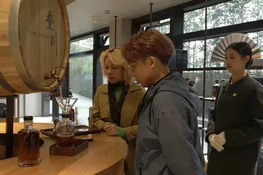 In this image from a video, visitors look at the bottling of a customized bottle of The Chuan whisky at the Chuan Malt Distillery in Emeishan in southwestern China's Sichuan province on Dec. 13, 2023. The more than $100 million distillery owned by Pernod Ricard and based at the UNESCO World Heritage site Mount Emei, launched a pure-malt whisky, The Chuan, aiming to tap a growing taste among young Chinese for whisky in place of the traditional "baijiu" used to toast festive occasions. (AP Photo/C