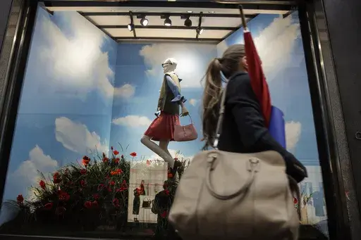 A woman walks past the Gucci store window at the Via Montenapoleone fashion district, during the Milan's fashion week in Milan, Italy, Friday, Sept. 25, 2020. The post-pandemic surge in global sales of luxury handbags, shoes and apparel is on pace to stall this year amid a creativity crisis and price hikes focused on the biggest spending customers. (AP Photo/Luca Bruno, File)