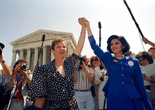 Norma McCorvey, Jane Roe in the 1973 court case, left, and her attorney Gloria Allred hold hands as they leave the Supreme Court building in Washington after sitting in while the court listened to arguments in a Missouri abortion case, April 26, 1989. A leaked draft of a U.S. Supreme Court decision suggests the country's highest court could be poised to overturn the constitutional right to abortion, allowing individual states to more heavily regulate or even ban the procedure. (AP Photo/J. Scott