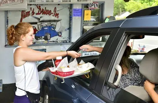  In this Tuesday June 23, 2015 photo, Jim's Drive-In waitress Aly King delivers an order to a waiting customer at the iconic restaurant in Lewisburg, W.Va. A program offering $20,000 in cash and incentives for remote workers to move to West Virginia as part of a population push has chosen 33 people for its second class of newcomers to live in the Greenbrier Valley, which includes Lewisburg. (Bob Wojcieszak/Daily Mail via AP, File)