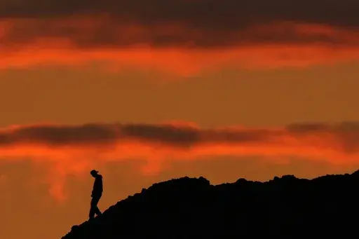 A person is silhouetted against the sky at sunset at Papago Park in Phoenix on Thursday, March 2, 2023. The homicide rate for older U.S. teenagers rose to its highest point in nearly 25 years during the COVID-19 pandemic, and the suicide rate for adults in their early 20s was the worst in more than 50 years, government researchers said Thursday, June 15. (AP Photo/Charlie Riedel)