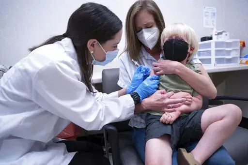 Pharmacist Kaitlin Harring, left, administers a Moderna COVID-19 vaccination to three year-old Fletcher Pack, while he sits on the lap of his mother, McKenzie Pack, at Walgreens pharmacy Monday, June 20, 2022, in Lexington, S.C. Today marked the first day COVID-19 vaccinations were made available to children under 5 in the United States. (AP Photo/Sean Rayford)
